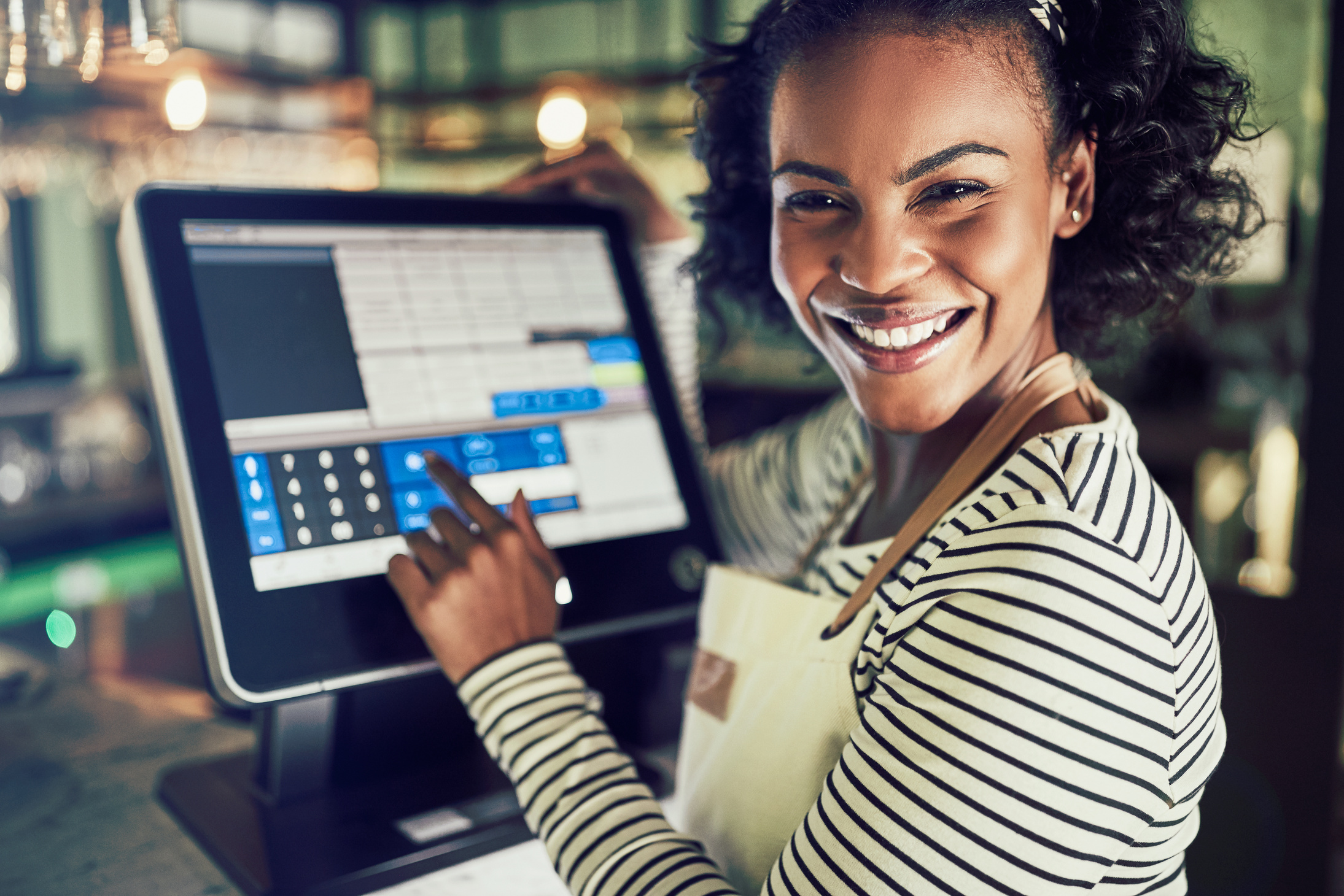 Smiling Young Waitress Using a Restaurant Point of Sale Terminal